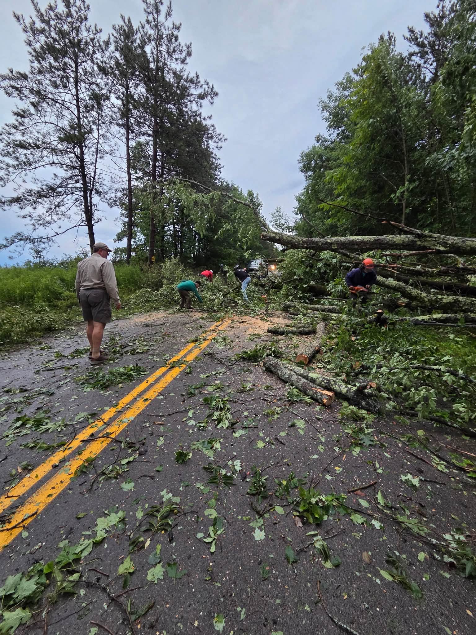 Neighbors and crew clearing a downed tree across the road after the July 18 tornado